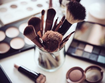 Professional makeup brushes and tools, natural make-up products set on white table.