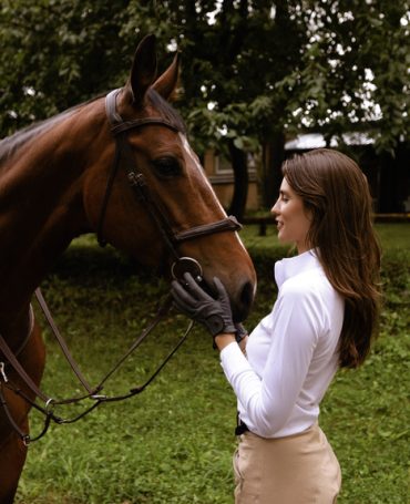 fashion outdoor photo of beautiful woman with dark hair posing with horse