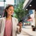 Portrait of an Attractive Japanese Female Wearing Smart Casual Clothes and Using Smartphone on the Urban Street. Manager in Big City Connecting with People Online, Messaging and Browsing Internet.