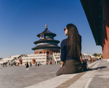 brunette girl sitting on the steps by temple of heven in China brunette girl sitting on the steps by temple of heaven in China. Brunette girl enjoying chinese architecture while sitting on the steps and relaxing. Caucasian tourist taking a break from exploring Beijing China by taking some time to herself.