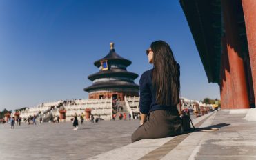 brunette girl sitting on the steps by temple of heven in China brunette girl sitting on the steps by temple of heaven in China. Brunette girl enjoying chinese architecture while sitting on the steps and relaxing. Caucasian tourist taking a break from exploring Beijing China by taking some time to herself.