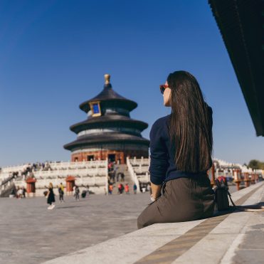 brunette girl sitting on the steps by temple of heven in China brunette girl sitting on the steps by temple of heaven in China. Brunette girl enjoying chinese architecture while sitting on the steps and relaxing. Caucasian tourist taking a break from exploring Beijing China by taking some time to herself.