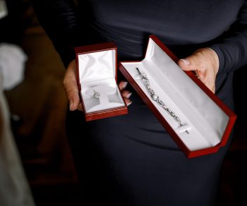 Lady in black dress holds red velvet boxes with jewels Lady in black dress holds red velvet boxes with jewels