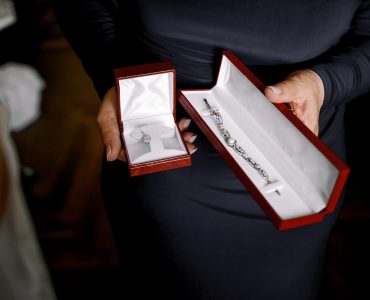 Lady in black dress holds red velvet boxes with jewels Lady in black dress holds red velvet boxes with jewels
