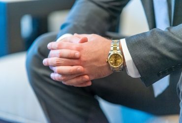 Shallow focus shot of a man in suit clasping his hands with a blurred background A shallow focus shot of a man in suit clasping his hands with a blurred background